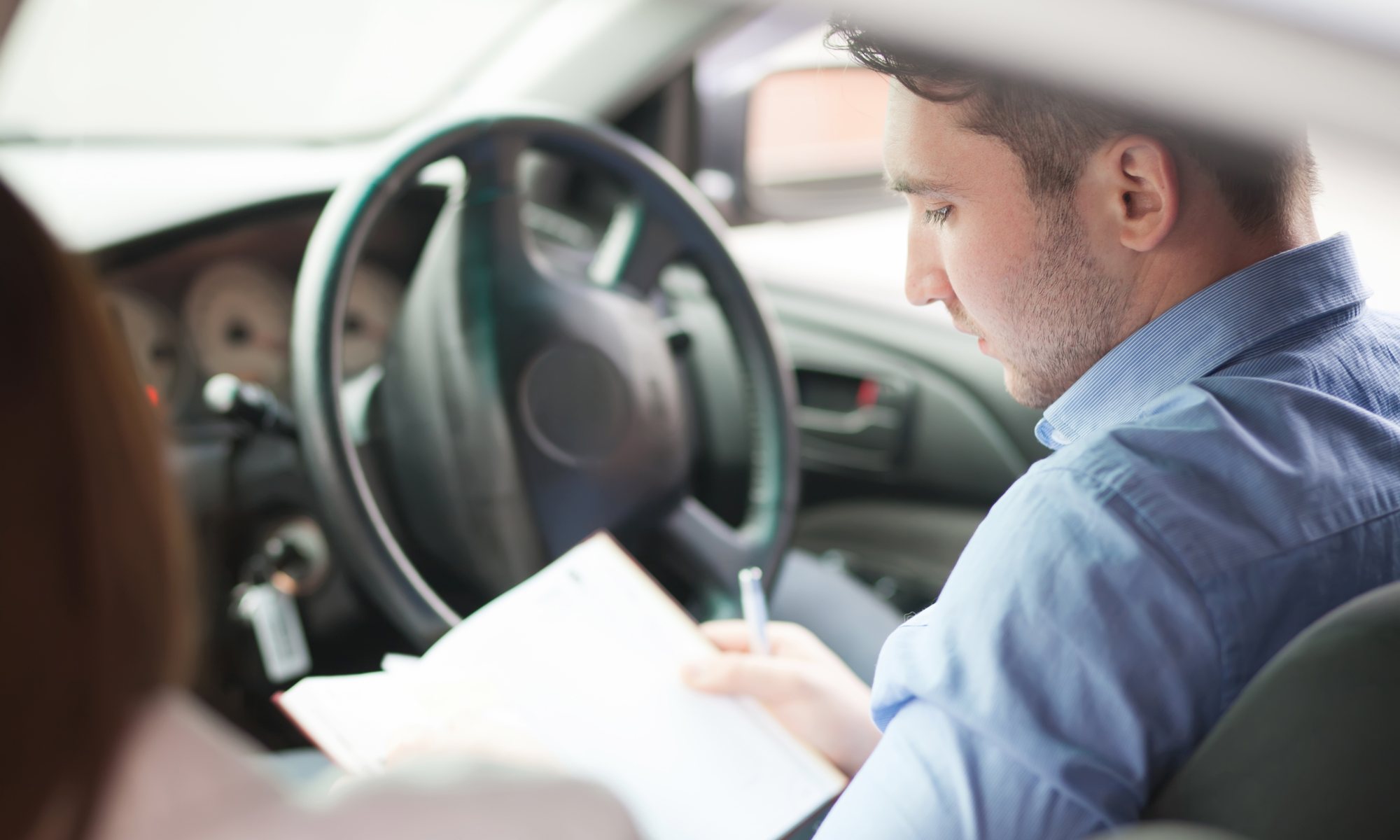 A sales rep logging a business trip in the vehicle logbook before driving off
